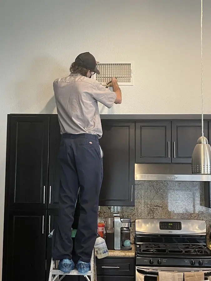 Technician inspecting an air vent during HVAC service in Fort Lauderdale